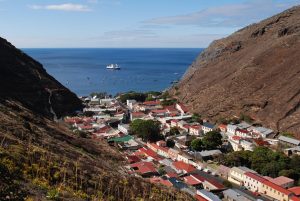 steep valley sides with a bay behind and on the valley floor a town in a narrow strip of land with red roofs