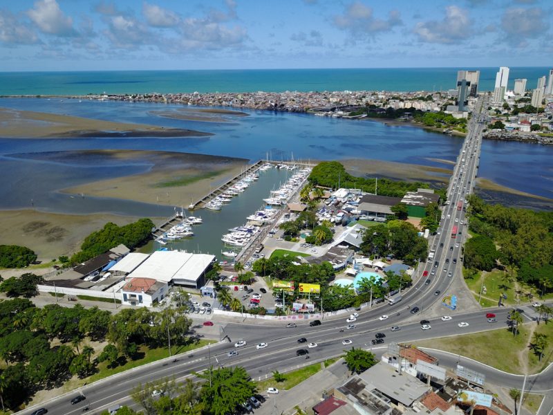 aerial view of a main road crossing over an estuary with this side of the estuary a canal and alongside marina with associated buildings